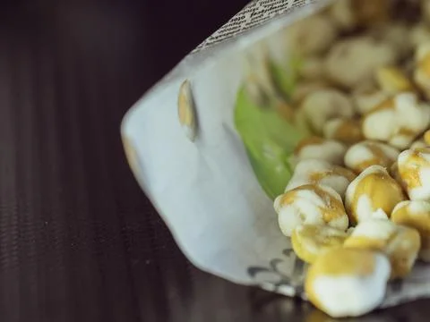 Crispy Roasted Corn Snack Spilling From Open Paper Bag On Dark Table Surfac.. Stock Photos