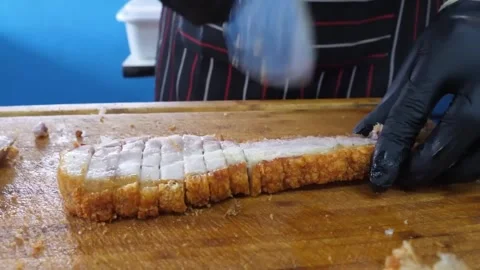 Crispy Roasted Pork Belly Slices on a Wooden Cutting Board Stock Footage 338212050