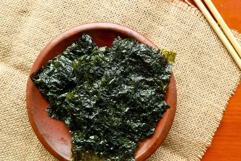 Crispy roasted seaweed snack on a rustic burlap background Stock Photos