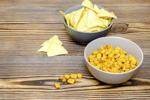 Crispy salt snacks, chips, nut, corn in bowl on wooden background close up... Stock Photos