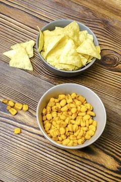 Crispy salt snacks, chips, nut, corn in bowl on wooden background close up... Stock Photos