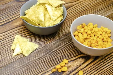 Crispy salt snacks, chips, nut, corn in bowl on wooden background close up. U Stock Photos