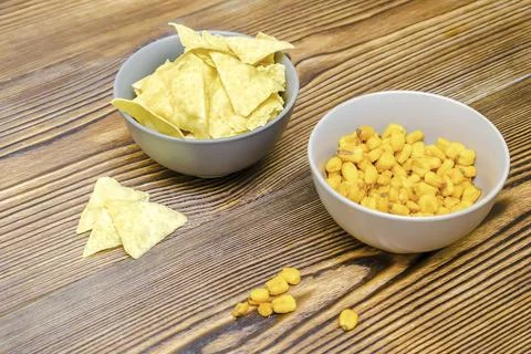 Crispy salt snacks, chips, nut, corn in bowl on wooden background close up... Stock Photos