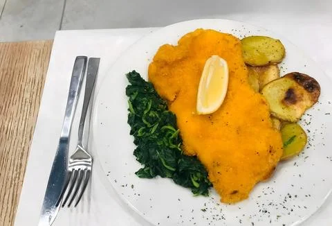 Crispy Schnitzel with Spinach and Roasted Potatoes 스톡 사진