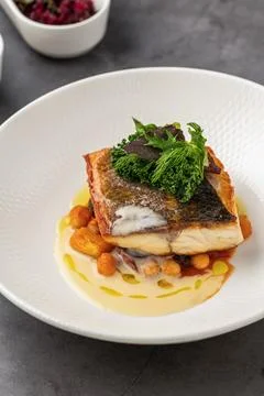 Crispy-skinned pan-seared fish fillet with chickpeas, creamy sauce, and fre.. Stock Photos