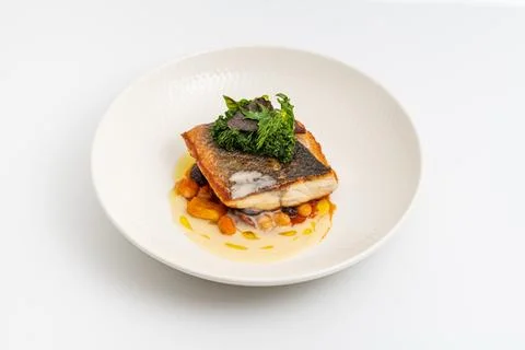 Crispy-skinned pan-seared fish fillet with chickpeas, creamy sauce, and fre.. Stock Photos