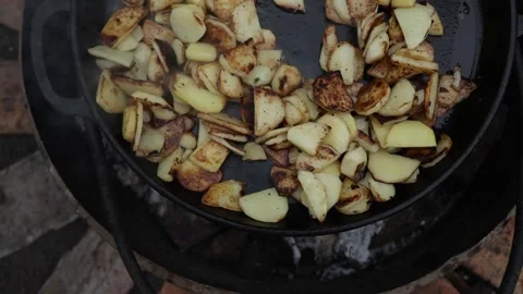Crispy Sliced Potatoes Sizzling in a Cast Iron Skillet Over Open Flames Stock Footage 337105928