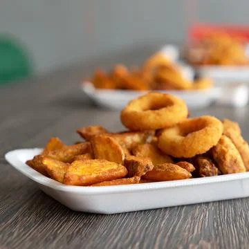 Crispy snack for Beer. Fried potato chips and rings on blurred background. Side Stock Photos