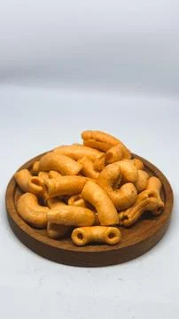 Crispy spicy macaroni snack served on a wooden plate on white background Stock Photos