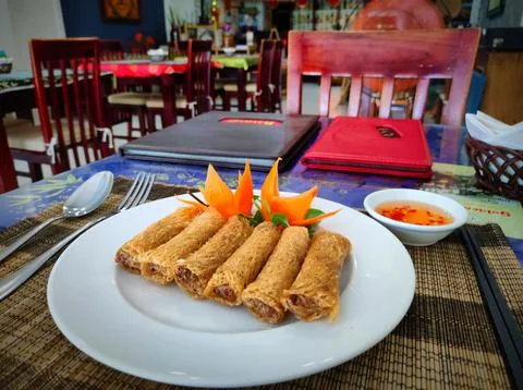 Crispy spring rolls served with sauce and garnished on a table in a restaur.. Stock Photos