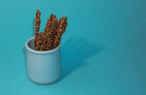 Crispy sticks with hazelnut sprinkles in chocolate on a blue background. Stock Illustration