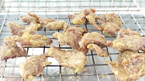Crispy Thai fried pork slices on a cooling rack draining oil. Vídeo Stock 343697734