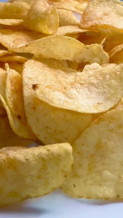Crispy yellow potato chips piled up on a plate Видео 334593332