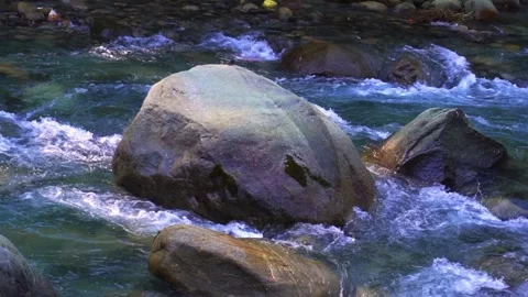 Cristal clear river flows in a slow motion around large stones in a Himalay.. 스톡 동영상 297259138