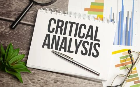 CRITICAL ANALYSIS words on notepad with magnifying glass and charts Stockfoto's