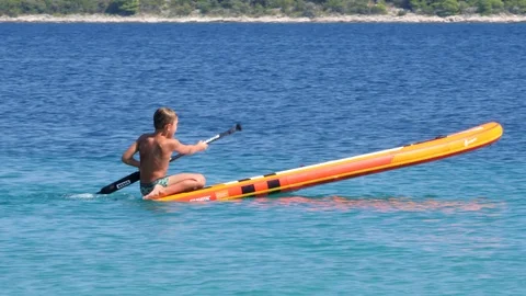 Croatia, Marina, Split-Dalmatia, August 21, 2019. A little boy sits on SUP Stock Footage 124687605