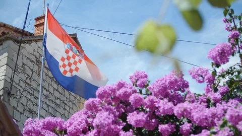 Croatian flag fluttering on wind, next to  flowers and old stone house. Stock Footage 97797249