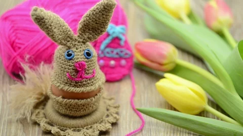 Crochet Easter bunny egg cup made of wool. fresh tulips and wool ball in back 스톡 동영상 87761633
