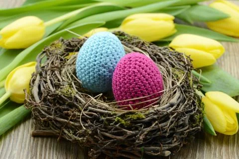 Crocheted easter eggs and  a bouquet of yellow tulips. Foto stock