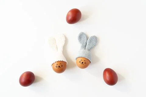 Crocheted Easter eggs with bunny ears and painted red eggs on a white backgro Stock Photos