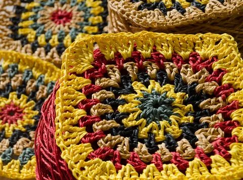 Crocheted raffia patterns. Granny square made of multi-colored raffia. Stock Photos