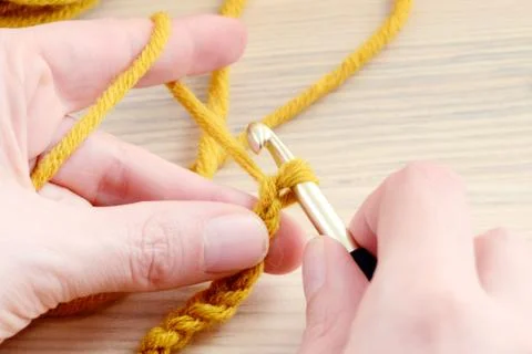 Crocheting with brown wool in hand. Stock Photos