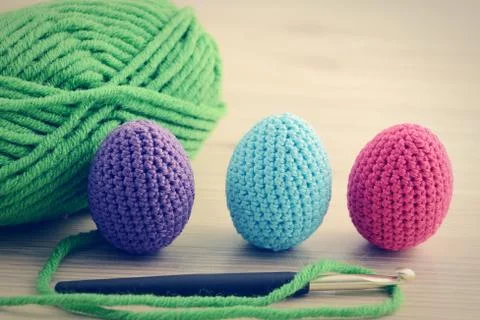 Crocheting easter eggs with blue pink green. wooden table background. Foto stock