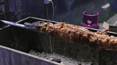Crocodile roasting on a rotating spit over coals 库存影片 335237197