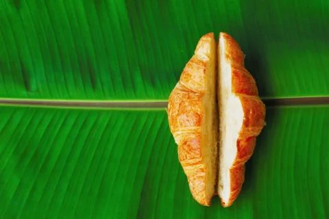 The croissant cut in the middle for stuffing placed on a bright green banana  Stock-Fotos