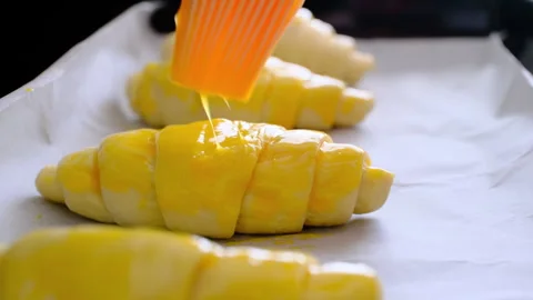 Croissant dough with egg applied to it to be put in the oven Stock Footage 289023246