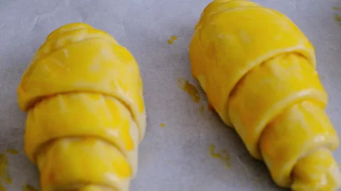 Croissant dough with egg applied to it to be put in the oven Stock Footage 289220140