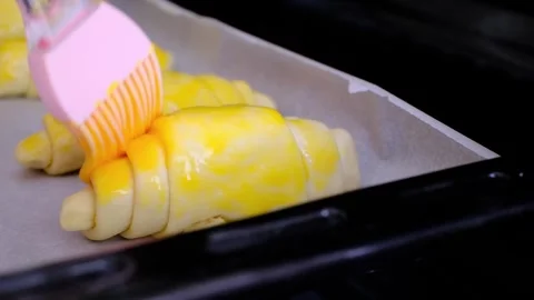 Croissant dough with egg applied to it to be put in the oven Stock Footage 289239639