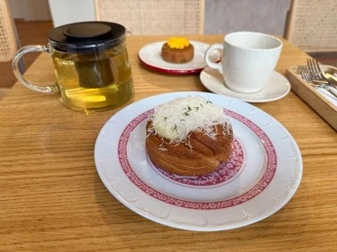 Croissant with grated cheese served on patterned plate with tea. Dining lifes Stock Photos