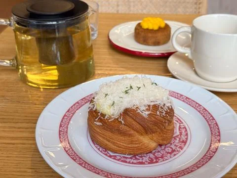 Croissant with grated cheese served on patterned plate with tea. Dining lifes Stock Photos