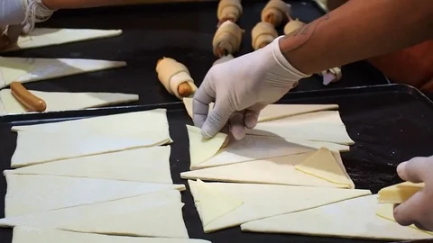 Croissant raw cut triangle dough on hot iron pan, preparing for sausage stuffing Stock Footage 81610649