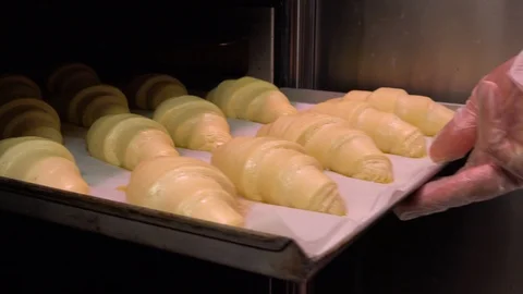Croissants on a baking sheet are pulled out of an oven - closeup Stock-Footage 103095481