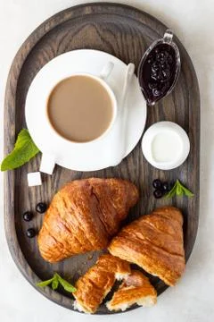 Croissants with a cup of coffee and jam on a dark wooden tray. Stock Photos