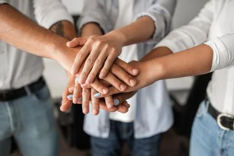 Crop anonymous colleagues stacking hands during work in office Stock Photos