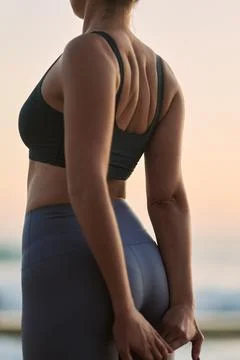 Crop anonymous lady doing stretching exercise on beach at sundown Foto stock