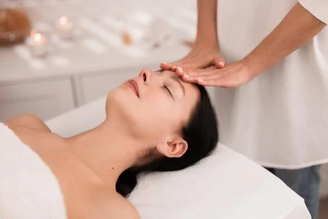 Crop anonymous masseuse doing face massage to female customer in salon Stock Photos