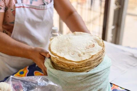 Crop baker putting pile of flatbreads in cloth bag at stall Stock Photos