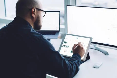 Crop bearded analyst watching tablet with illustrations at work Stock Photos