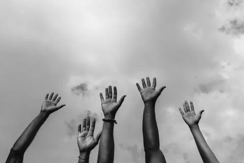 Crop black BLM activists with hands up under cloudy sky Stock Photos