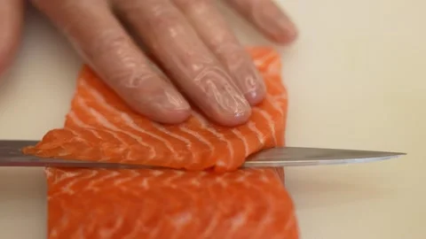 Crop chef cutting thin slices of salmon with sharp knife Stock Footage 250597234