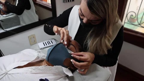 Crop cosmetologist applying patch on face of black woman Stock Footage 154303420