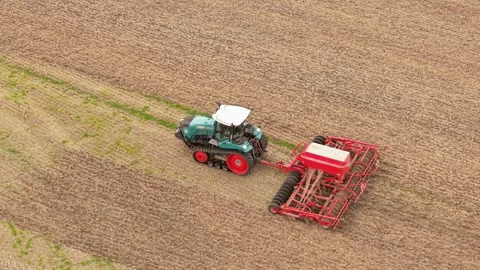 Crop establishment with tractor and red seed drill across harvested field. Wide Stock Footage 345501191