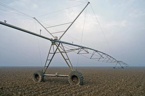 Crop Irrigation using the center pivot sprinkler system in the winter fog . Stock Photos