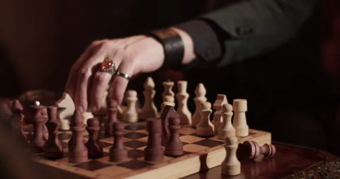 Crop man playing chess board game in dark room Stock Footage 260559221