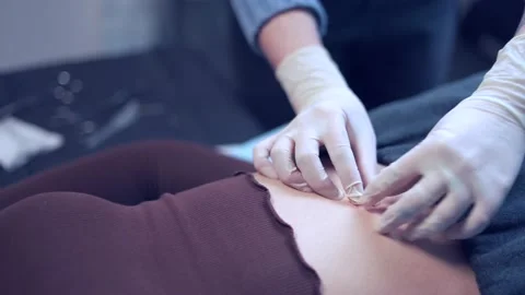 Crop piercer inserting piercing into belly button Stock Footage 195282763