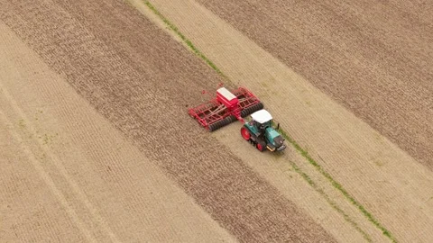 Crop seeding with tracked tractor and wide agricultural planter on prepared soil Stock Footage 346604873
